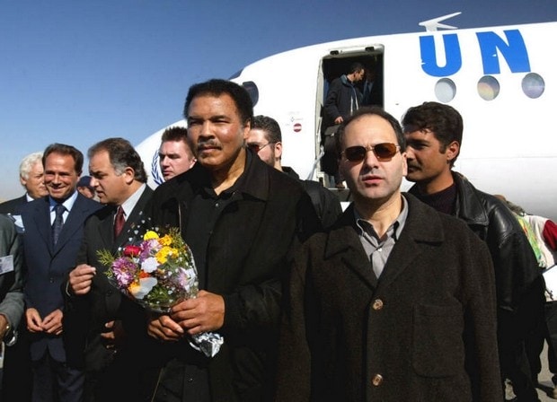 Muhammad Ali and a group of people in suits and coats standing in front of a UN plane