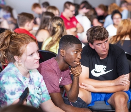 A seated group of young visitors engaged in listening.