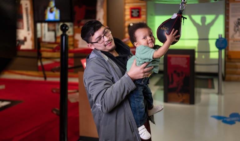 Father and toddler child in the Deer Lake exhibit playing with a speed bag