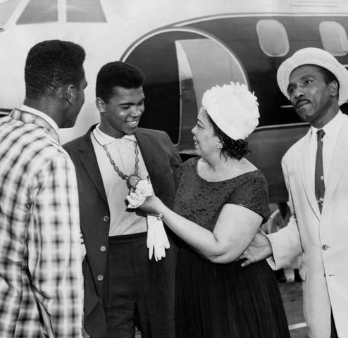 Black and white photo of Muhammad Ali and family as he wears his gold medal