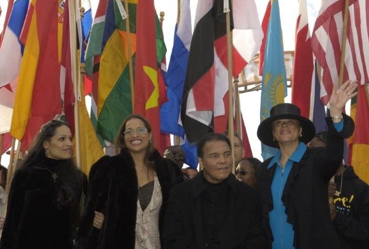 Photo of Muhammad Ali, Lonnie and two daughters with flags behind them