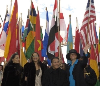 Photo of Muhammad Ali, Lonnie and two daughters with flags behind them