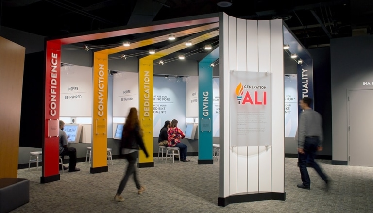 Museum guests sitting in Generation Ali booths while others walk by