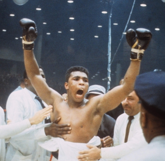 Photo of Muhammad Ali celebrating with gloves in the air