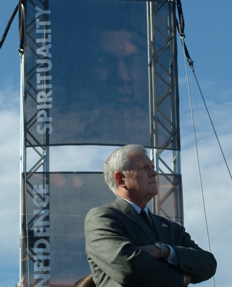 Man stands with arms crossed in front of Muhammad Ali banner