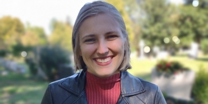 Woman wearing red shirt and leather jacket smiling for camera