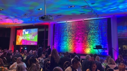 Ballroom full of people attending an event and a colorful empty stage