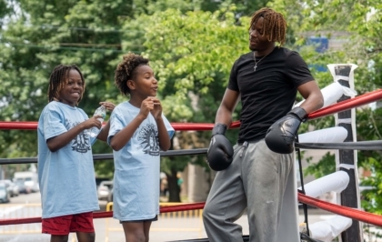 Two kids in boxing ring learning with mentor