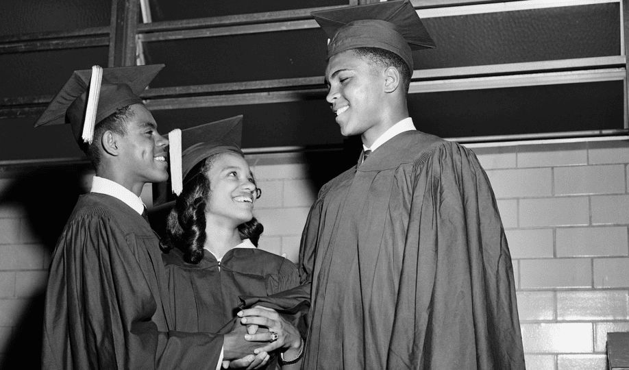 Muhammad Ali in graduation cap and gown shaking hands with students